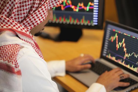 Emirates polgár háttérben egy laptom, melyen egy grafikont néz.