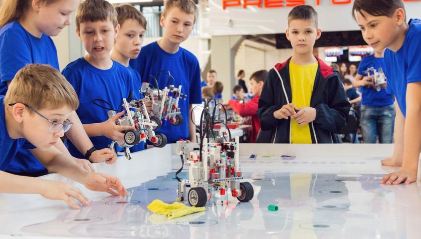 Students in blue shirts building and programming a robot.