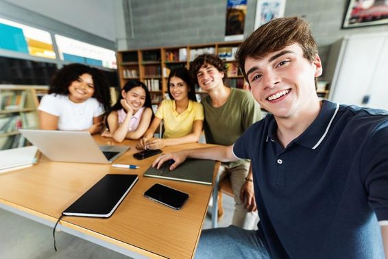 学生在图书馆学习，桌上放有笔记本、手机和纸质记事本。