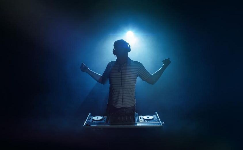 Egy ember áll a dj pult mögött. 