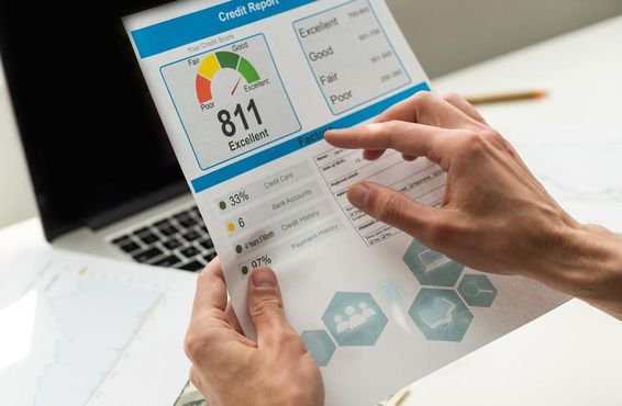 Bank hitel kredit pontszámot olvas egy ember keze látszik, hátérben egy kikapcsolt notebook.
