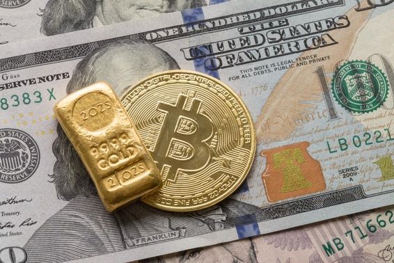 Egy 100 dolláros bankó felett egy befektetési arany tömb és egy bitcoint érme. 