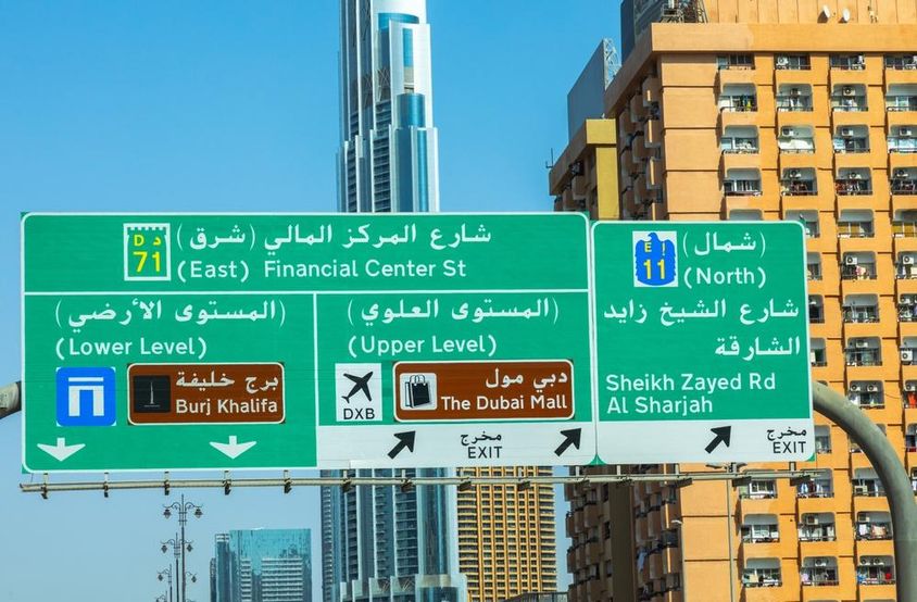 Dubai felhőkarcolok a háttérben, előtte útjelző tábla.