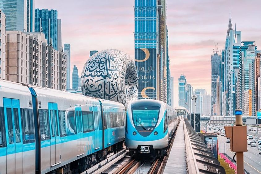 Dubai metrók láthatóak a képen háttérben felhőkarcolok és a jövő múzeum.