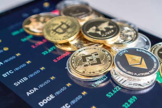 Eterium és bitcoint érmék vannak egy telefon előlapjára rakva amin a criptotozsde árai láthatóak.