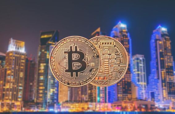 Bitcoin érmék vannak előtérbe, hátul felhőkarcolok látszanak.