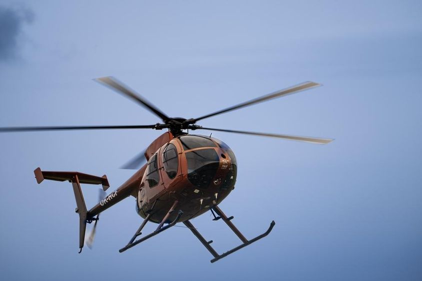 Egy könnyűtestű helikopter repül a levegőben. 