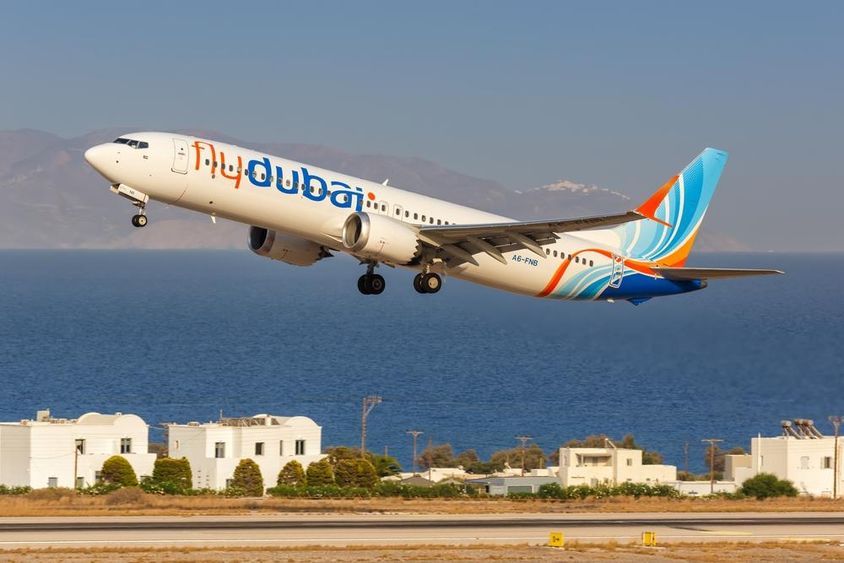 Flydubai gép repül kis magasságban , mögötte fehér apró házak és a tenger. 