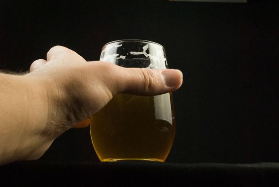 一只手握着一个啤酒杯，仅能看到手和杯子。