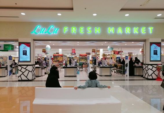Lulu bolt bejárata egy plázába, előtte 2 ember ül egy nő és egy gyerek, hátulról látszanak. 