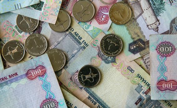 Dubai papírpénz szétdobálva asztalon felette 1 dirhamos érmék. 