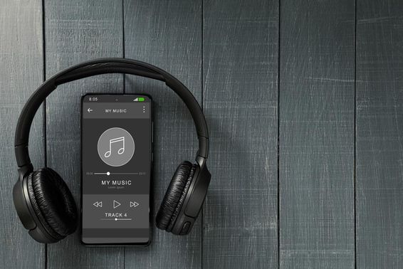 Reprodução de música circulando em um telefone, com fones de ouvido ao lado.
