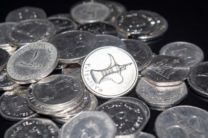 A handful of 1 dirham coins scattered around.