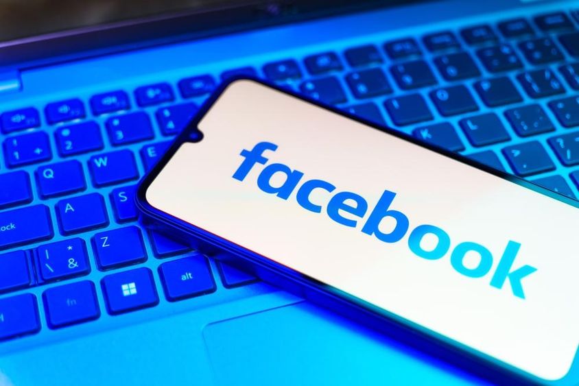 Facebook on a phone, keyboard underneath.
