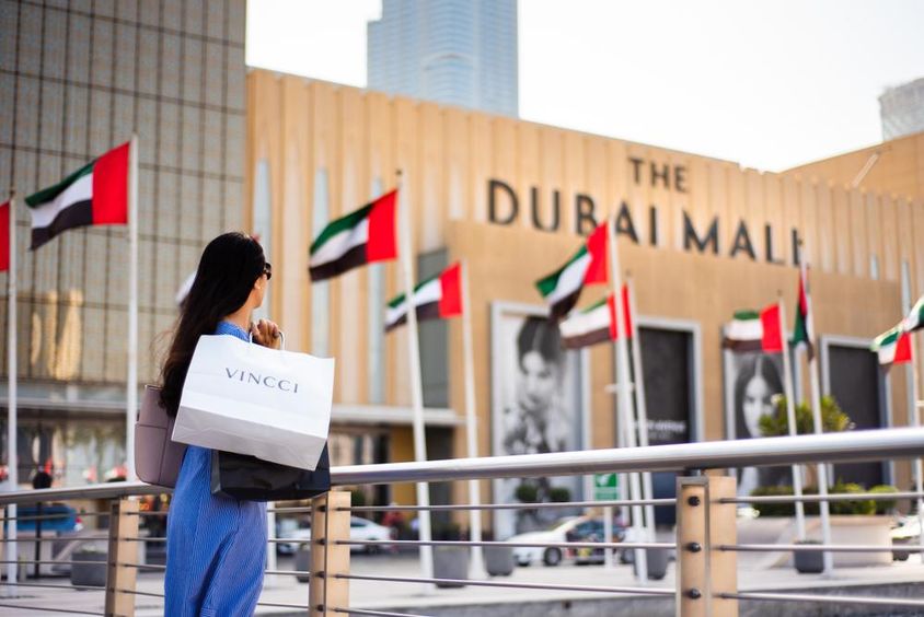 Arab woman with shopping bags in front of Dubai mall.