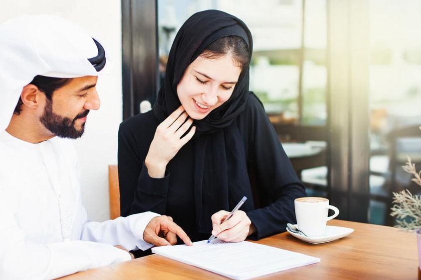 Arab férfi dokumentumokat ad aláírásra egy hidzsábot viselő nőnek.