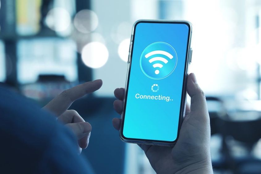 Az okostelefont használó férfi csatlakozik a vezeték nélküli internethez (Wi-Fi) az okostelefonon.