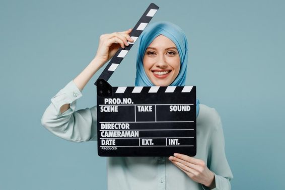 Fiatal arab muszlim nő abaya hidzsábban, kezében klasszikus fekete film csapó.