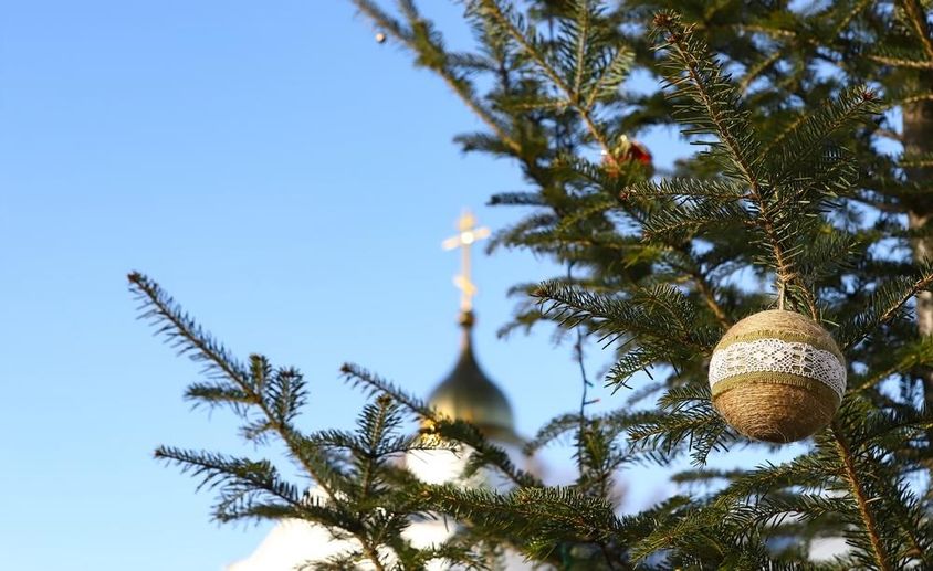 Karácsonyfa ága díszekkel, háttérben egy ortodox kereszt feszülettel