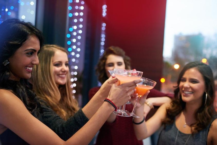 Lányok alkohollal koccintanak koktélbárban.