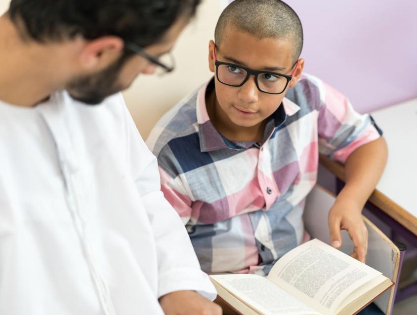 Fiatal arab tanár tanul egy iskolás fiúval.
