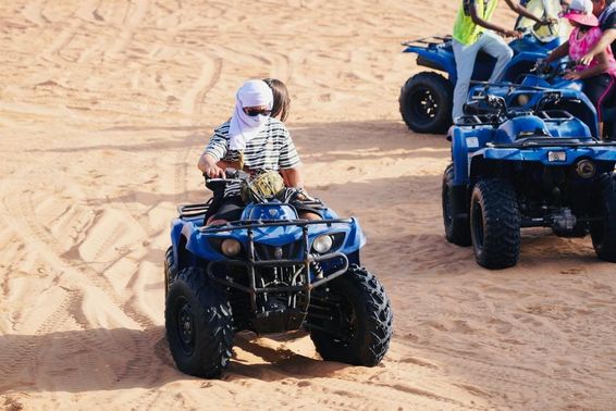 Jovem casal andando de quadriciclo no deserto de Dubai.