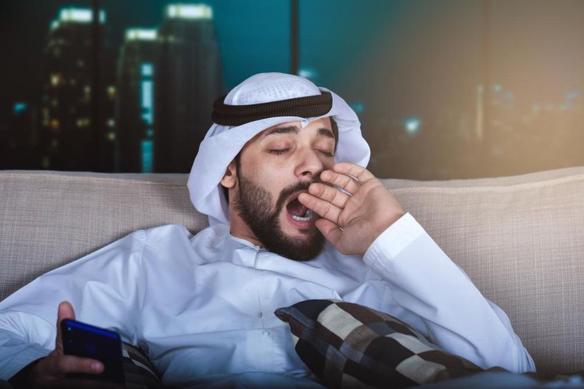 Arab man yawning while watching television.