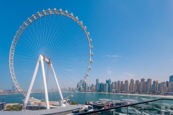 Roda-gigante Ain Dubai com arranha-céus e mar ao fundo.