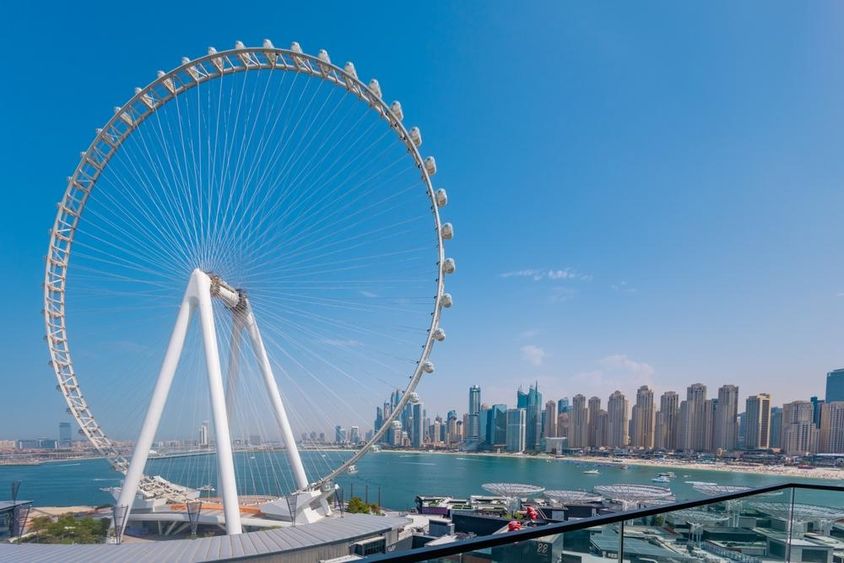 Ain Dubai Ferris wheel with skyscrapers and sea in the background.
