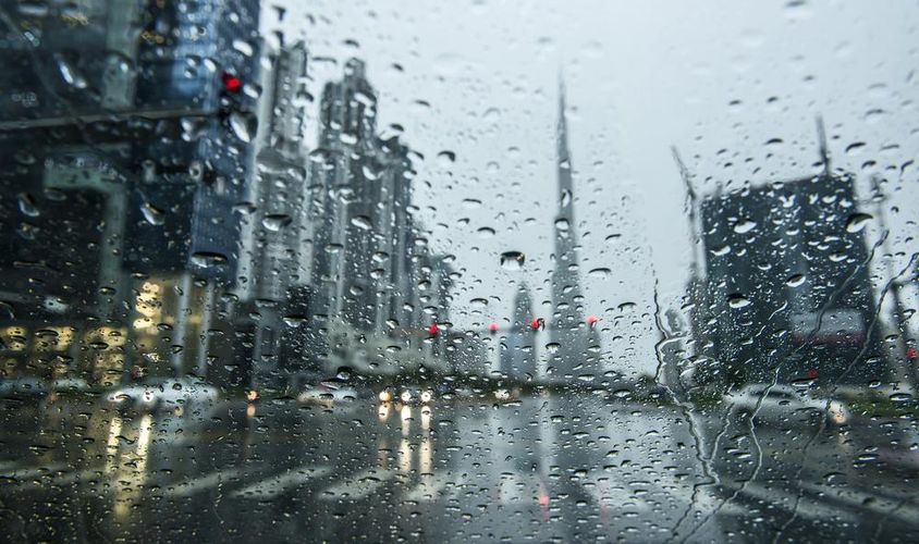 Eső Dubajban, esős üveg mögött homályos kilátás látható, háttérben a burj khalifa sziluettje.