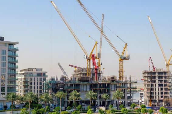 Építés alatt álló lakóépületek darukkal az építkezésen, Dubai Creek kikötőjében.