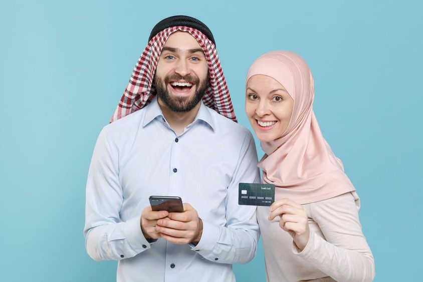 Smiling couple holding credit card and phone.