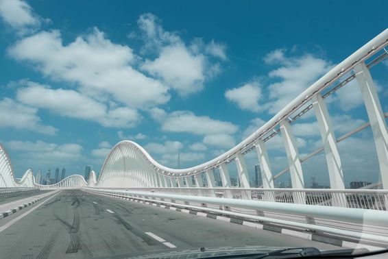Ponte abstrata moderna com céu azul e nuvens ao fundo.
