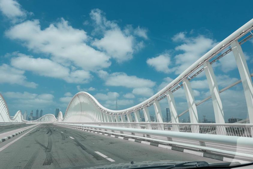 Modern abstract bridge with blue sky and clouds in the background.