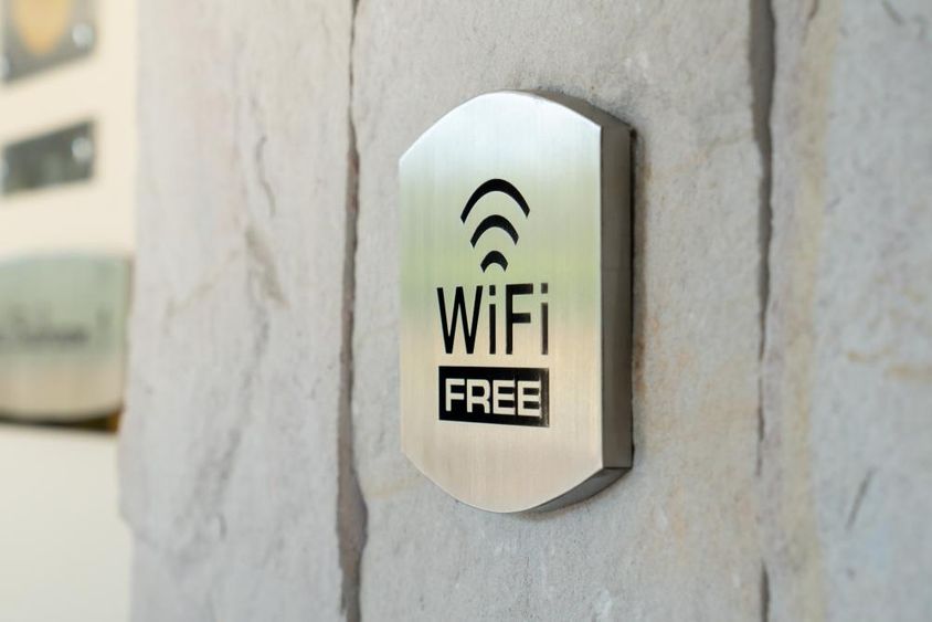 Metallschild mit WIFI-Symbol an einer Hotelwand.