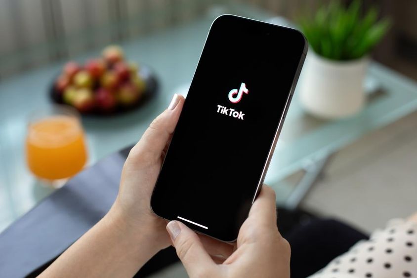 Női kezében Apple iPhone 15 Pro Max, TikTok videó a képernyőn.