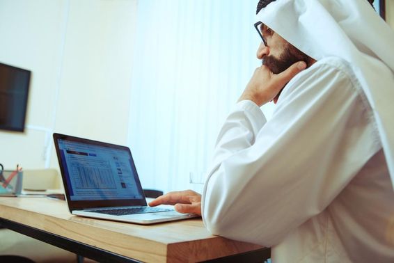 Arab üzletember online dolgozik számítógépen kényelmes irodájában.