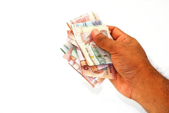 Dirham bankjegyek egy férfi kezében. 