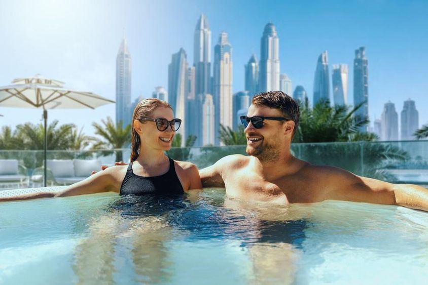 Boldog fiatal pár pihen a szabadtéri pezsgőfürdőben a Dubaiban.