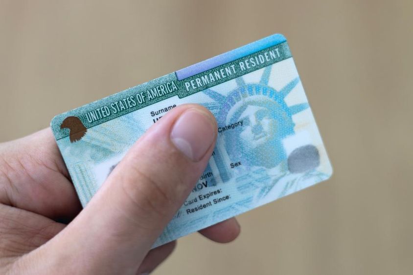 A permanent resident in the U.S. holds a green card in hand.