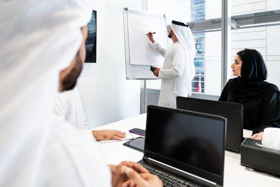 Hagyományos emírségi ruhát viselő üzletemberek csoportja találkozik az irodában Dubaiban.