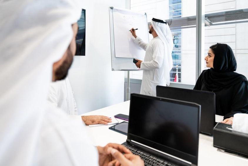 Hagyományos emírségi ruhát viselő üzletemberek csoportja találkozik az irodában Dubaiban.