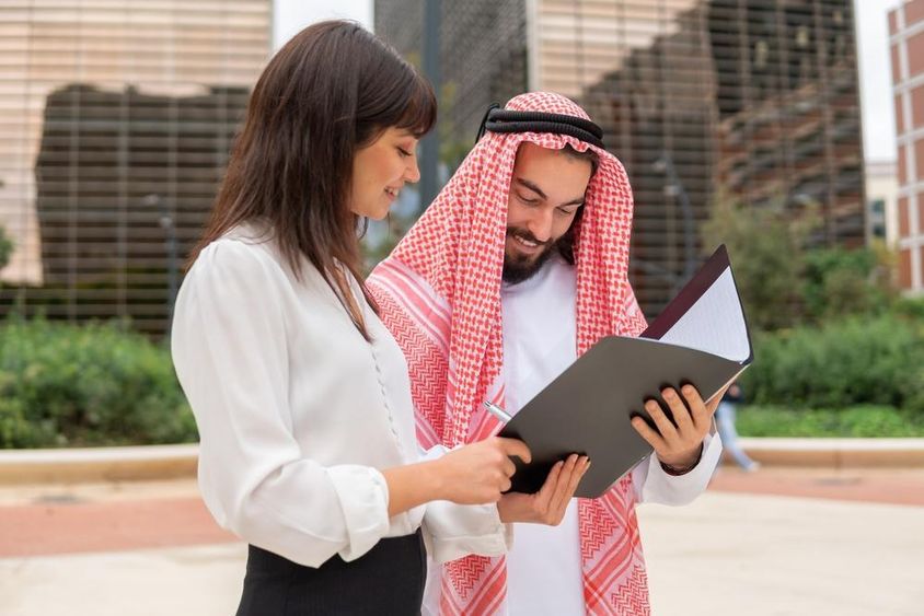Üzletasszony szerződés részleteit mutatja az arab férfi ügyfélnek.