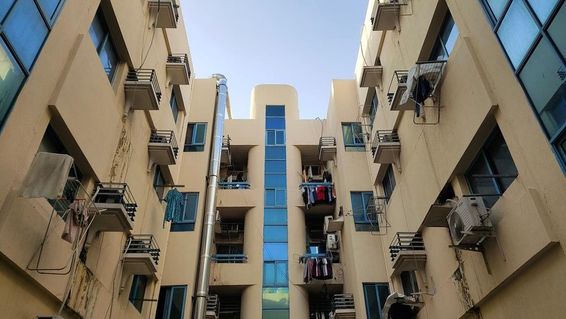 Dubai olcsó lakószoba bérelhető épület erkélye légkondicionálással és ruhákkal.