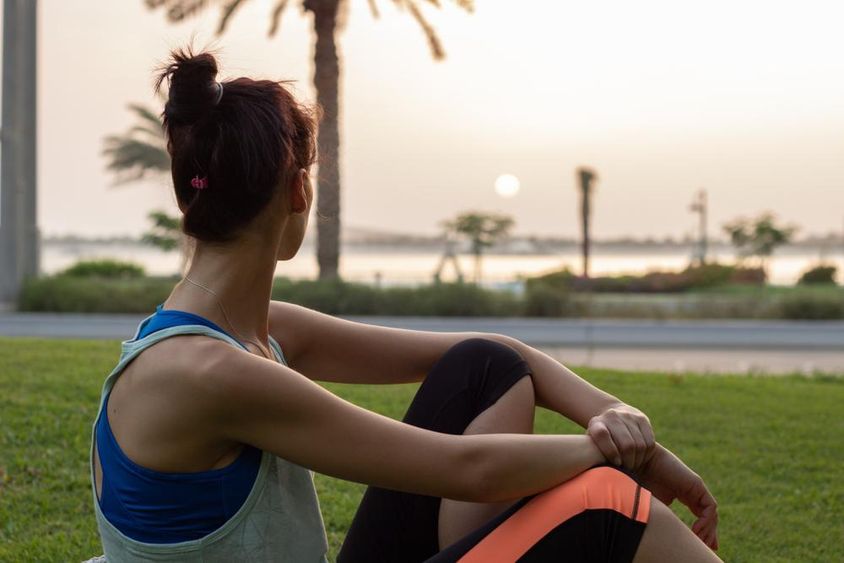 Fiatal lány pihen jóga után egy parkban Abu Dhabi Corniche-ban.