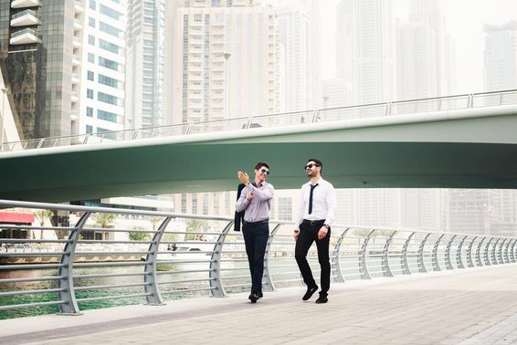 Zwei Geschäftsleute plaudern beim Gehen in Dubai Marina.