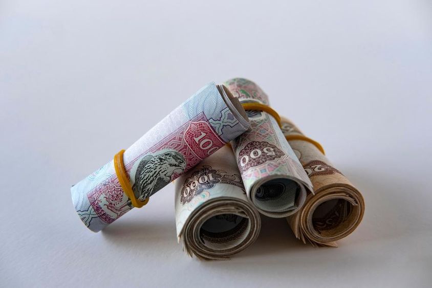 UAE dirham valuta és érmék gyűjteménye feltekerve és egymásra rakva.