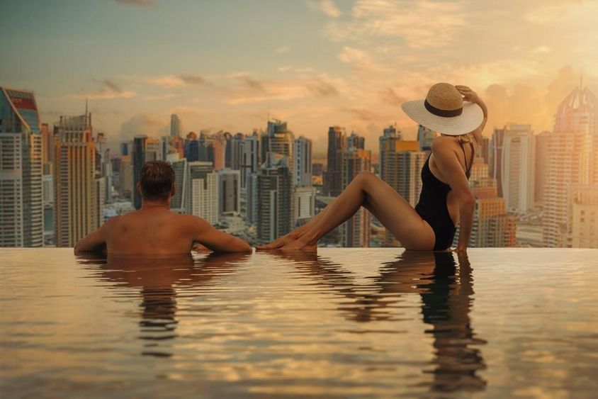 Pár élvezi Dubai látképét felhőkarcolók építészetével végtelenített medencéjéből naplementekor. 