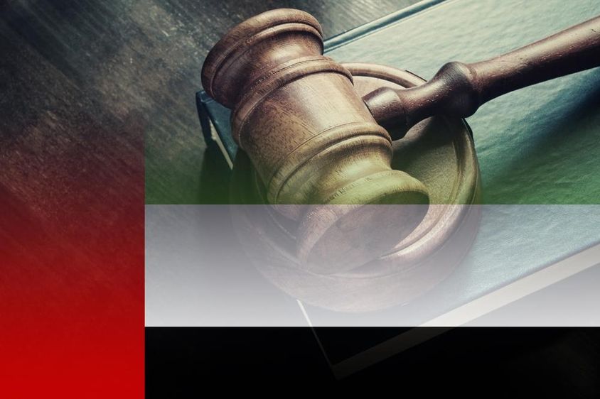 Bírói kalapács könyvvel az asztalon és az Egyesült Arab Emírségek zászló.