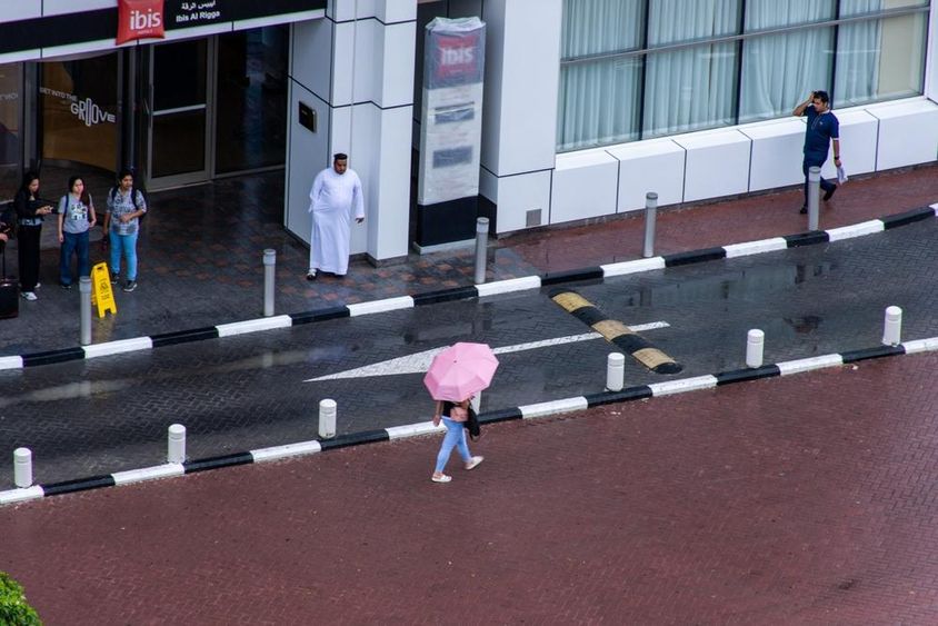 Egy esernyős lány az esőben sétál Dubai City-ben.